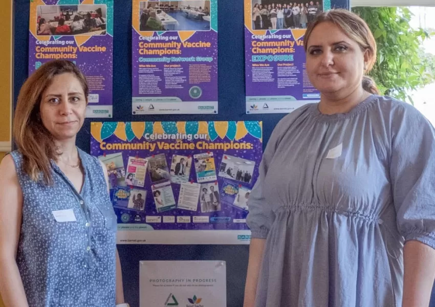 Community Network Group posing in front of poster display of the community vaccine champion case studies 