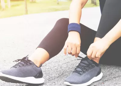 person sitting on floor, tying running shoes