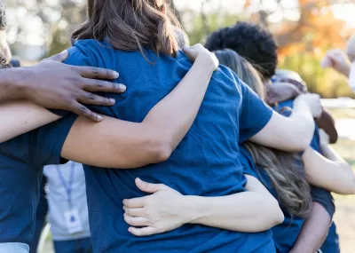 people outside in a circle with arms around each other