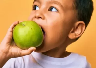 a young boy eating a big green apple