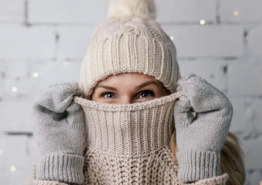 A person wearing winter clothing including a bobble hat and gloves.