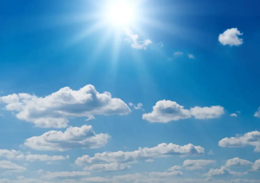 Blue sky with the sun shining and white clouds.