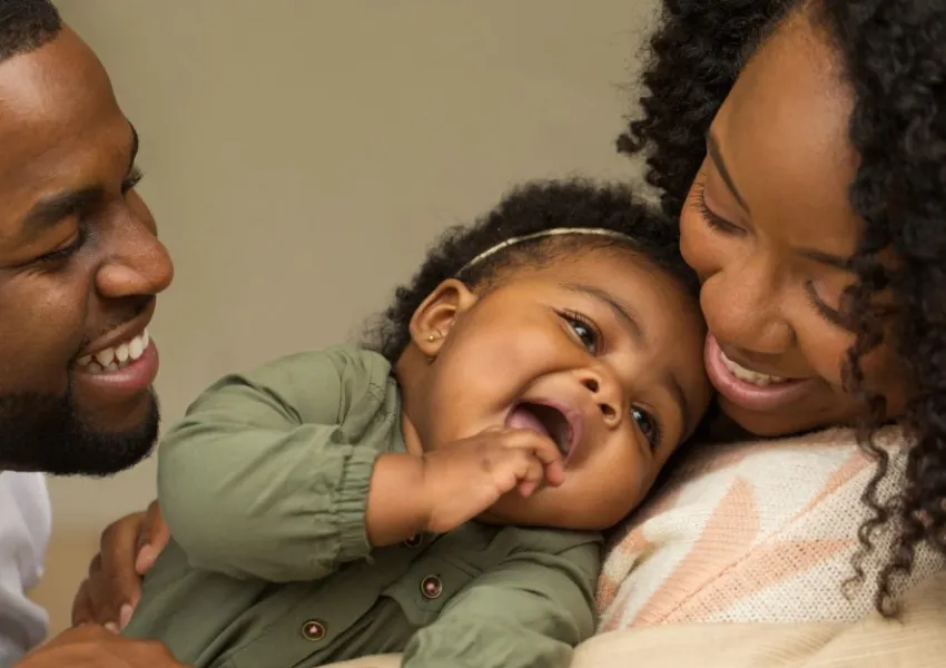 A young family. The parents and child are smiling.