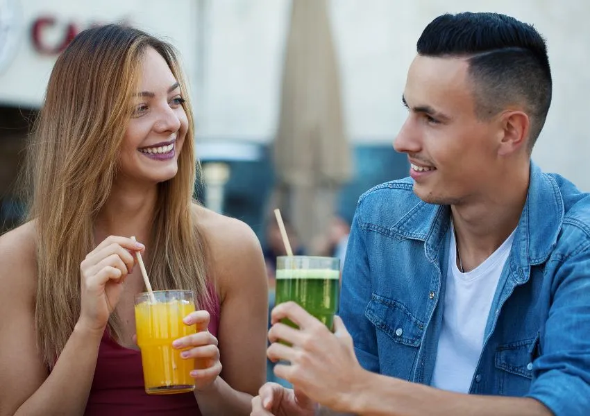 Two people, both holding a drink, smiling.