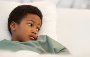 A young sick boy lying in bed