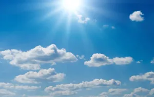 Blue sky with the sun shining and white clouds.