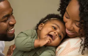 A young family. The parents and child are smiling.