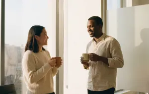 Two people, each holding a mug, talking and smiling.