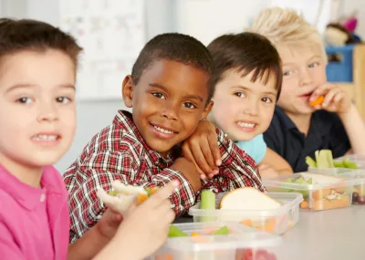 Smiling children at a table, eating food together