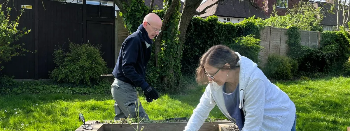 two people gardening in a raised bed outdoors 