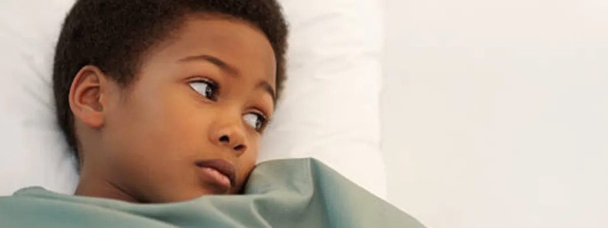A young sick boy lying in bed