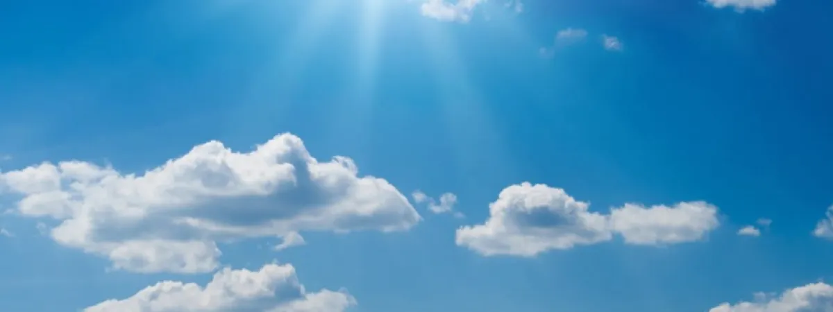 Blue sky with the sun shining and white clouds.