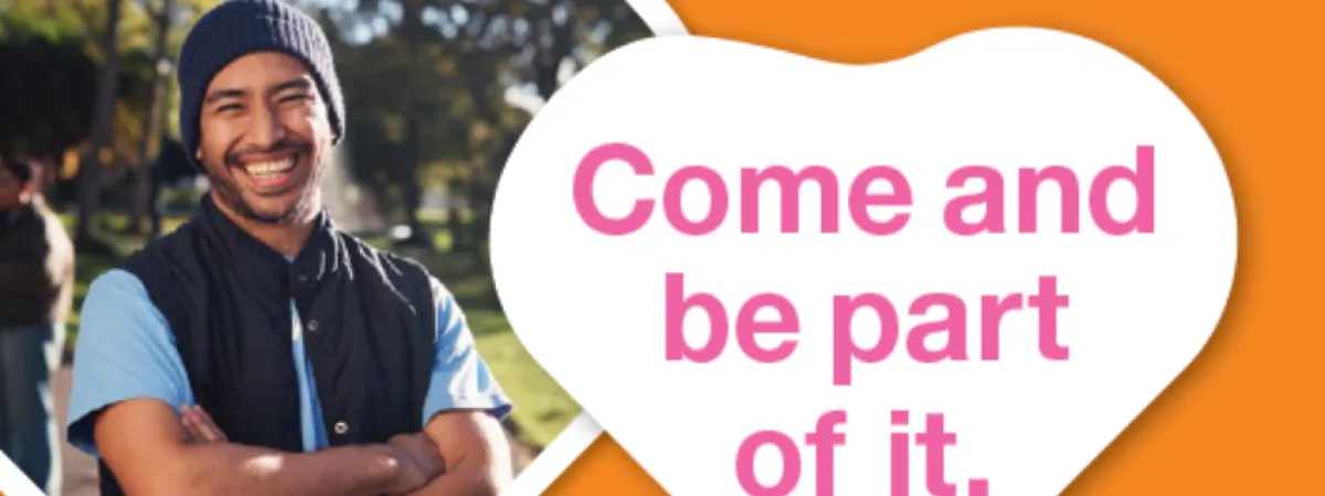 Smiling man in beanie, outside on sunny day. Orange background, pink writing in white heart 'come and be part of it'. #RecoveryMonth